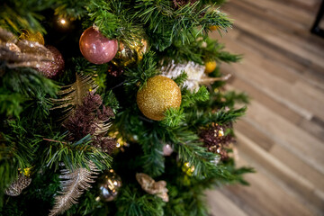 A shiny golden ball on a branch.Christmas tree decorations. New Year's decorations in pink and golden tones. Congratulations on winter holidays. Preparation for the celebration. Postcard.