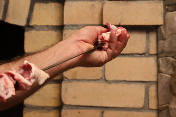 stringing fresh lamb on barbecue skewers in the fireplace