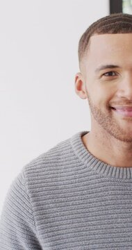 Vertical video half portrait of biracial man smiling to camera and laughing indoors with copy space