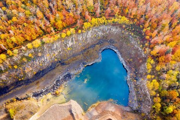 Luftaufnahme eines Wasserteichs in einem Wald mit üppigen Bäumen in Herbstfarben © Mk Lichtbild/Wirestock Creators