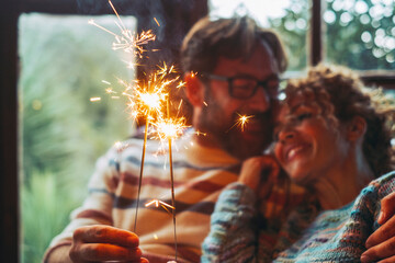 Love and romantic leisure activity with man and woman holding fire sparkler light together hugging...