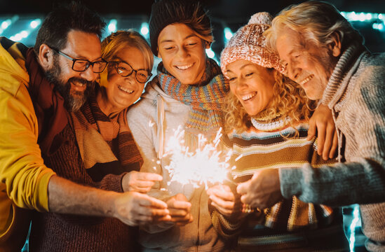 Colorful image of group of family people from young to adult and matures have fun together in friendship with sparklers light during christmas and ne year eve holiday time. Happy people leisure