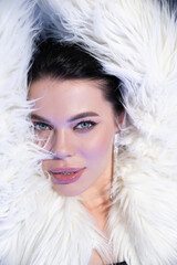 Portrait of fashionable model in faux fur jacket posing on blue background.