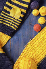 Hobbies and knitting concept. Yellow and brown knitting and balls of wool on dark rustic table. Copy space