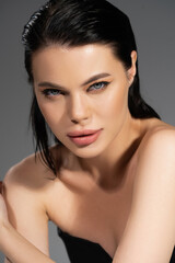 Fototapeta premium Pretty brunette woman with wet hair looking at camera isolated on grey.