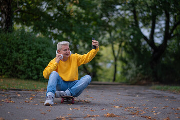 A woman sits on a skateboard and looks into her phone and does salfy