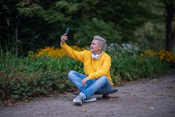 A woman sits on a skateboard and looks into her phone and does salfy