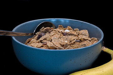 A bowl of bran flakes with dried fruit including banana and raisins