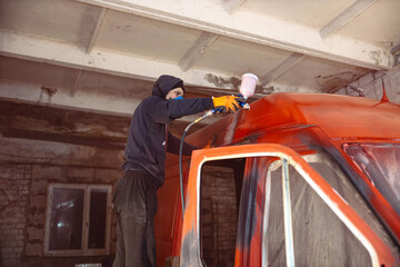 Fototapeta na wymiar Spray painting a van car red. Restoration and body repair of cars