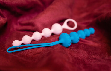 Woman holding anal balls in bed close-up.