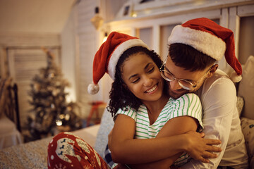 Happy black woman and her boyfriend embracing while spending Christmas together.