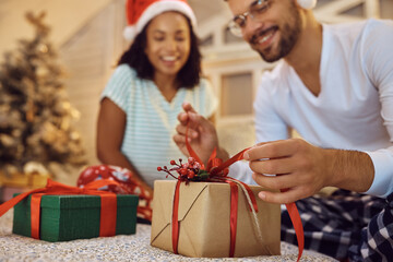 Close up of couple opening Christmas presents at home.