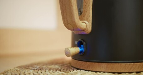 switching on the electric kettle by the human hand | home kitchen equipment