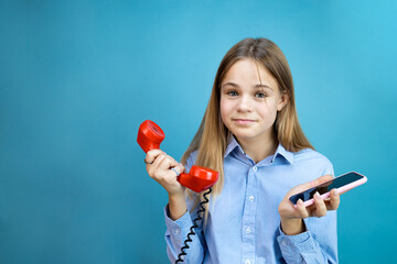 girl holding a retro phone and smartphone in her hand on a blue background