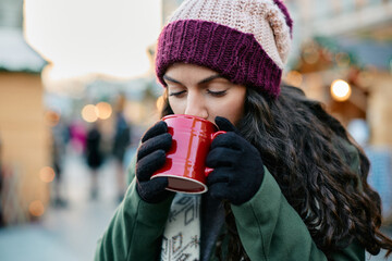 Young woman drinks mulled wine on Christmas fair in city.