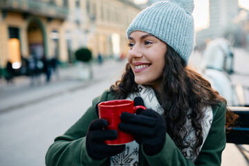 Young woman drinks mulled wine while enjoying in carriage ride on winter day.