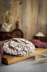 Natural homemade bread baked from rye flour. Composition with ears of wheat.