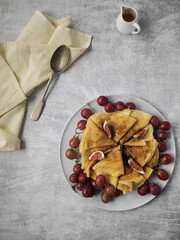 Pancakes with figs and red grapes, sprinkled with honey.