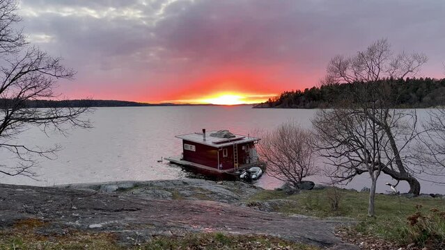 Boathouse floating at a Swedish lake called M&auml;laren or Malaren. One beautiful sunset at golden hour. Spring weather. Stockholm, Sweden, Scandinavia, Europe.
