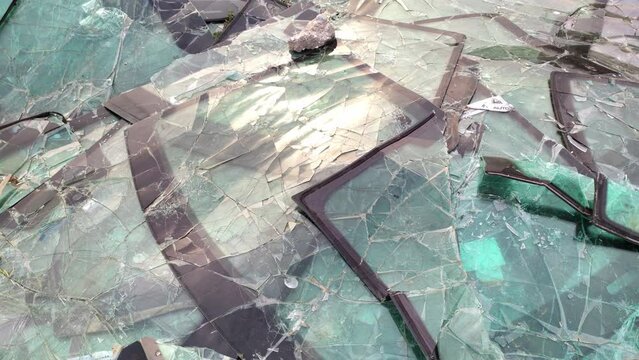 Pile of broken windshields - heap of cracked windscreens at a dump, due to traffic accidents. Windows for vehicles are made of safety laminated treated glass.