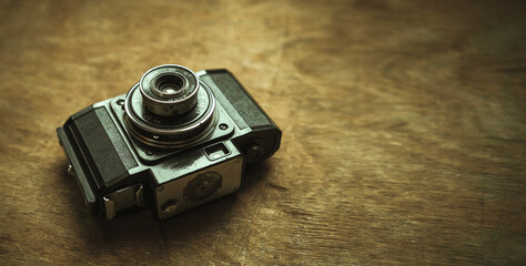 Black vintage film camera on a wooden table in retro style. Shooting analog photography. A plastic...