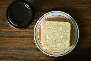 Emparedado de jamon y cafe en un vaso desechable. Vista superior, espacio para texto lado derecho.