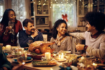 Happy friends enjoying in Thanksgiving dinner party at dining table.