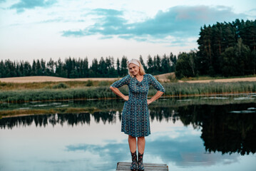 A beautiful woman is resting on a cool summer evening by a beautiful blue lake in the country