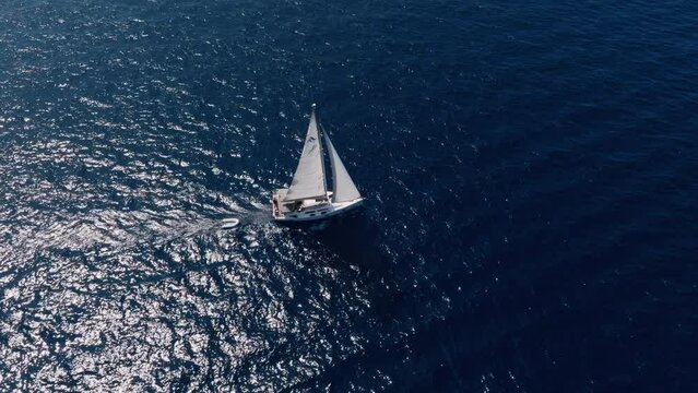 Aerial shot of sailboat sailing with open sails on a sunny day