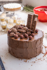 working in pastry, decorating a chocolate cake with cocoa cream and chocolates, delicious dessert at work place