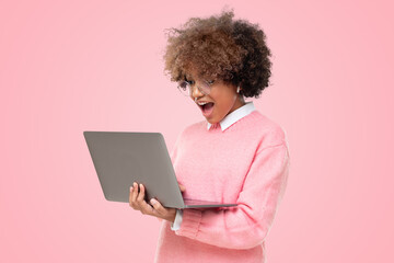 Studio portrait of surprised african american student teen girl, holding laptop with wow emotion