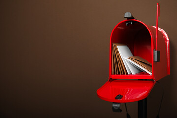 Open red letter box with envelopes against brown background. Space for text