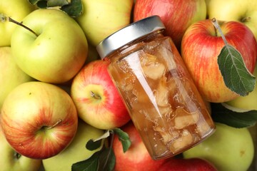 Delicious apple jam in jar on fresh fruits, top view