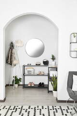 Hallway interior with stylish furniture and round mirror on light wall