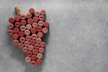 Grape made of wine corks with different dates on grey table, top view. Space for text