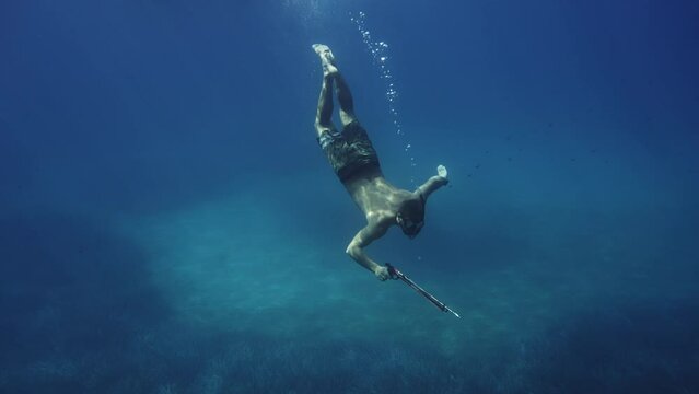 Underwater shot of guy with spare fishing harpoon swimming in croatian sea