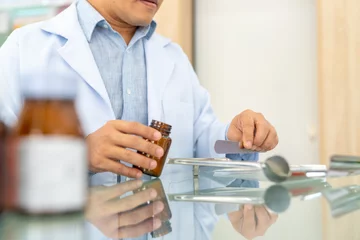 Fotobehang Medical pharmacy and healthcare providers concept. Asian man professional pharmacist counting drug pills on counting trays by hospital prescriptions on counter to patient customer in modern pharmacy. © CandyRetriever 