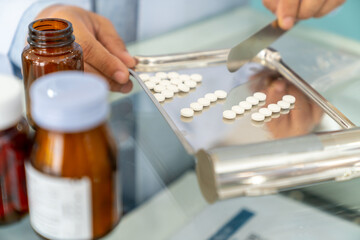 Medical pharmacy and healthcare providers concept. Asian man professional pharmacist counting drug pills on counting trays by hospital prescriptions on counter to patient customer in modern pharmacy.