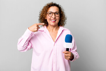 pretty middle age woman smiling confidently pointing to own broad smile. tv presenter with a...