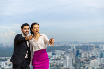 Caucasian couple celebrating holiday event having dinner at luxury skyscraper outdoor rooftop restaurant bar at summer sunset. Man and woman enjoy city lifestyle looking at city skyline in the evening