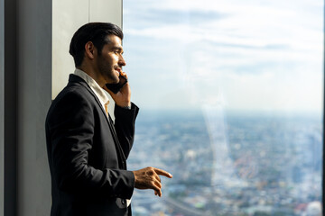  Confident Caucasian executive businessman in suit standing by the window at skyscraper office...