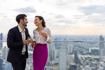 Caucasian couple celebrating at luxury skyscraper rooftop bar at summer sunset. Confident man and...