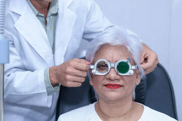 Attractive male ophthalmologist is checking eye vision of middle aged woman in modern clinic, doctors and ophthalmology clinic patients.