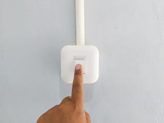 The finger switching one off on wall-mounted  switch in a close up conceptual view of power, energy...