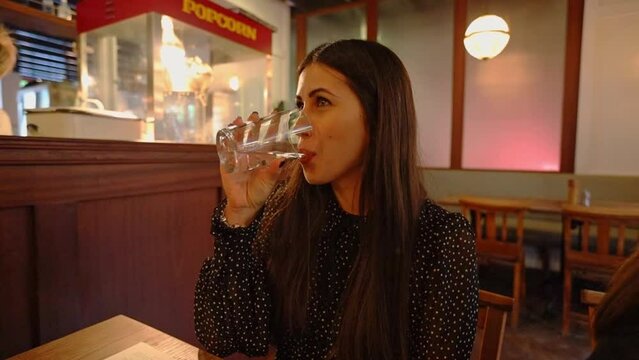 young caucasian lady girl business woman drinking water sitting in a retro cafe shop waiting for dinner
