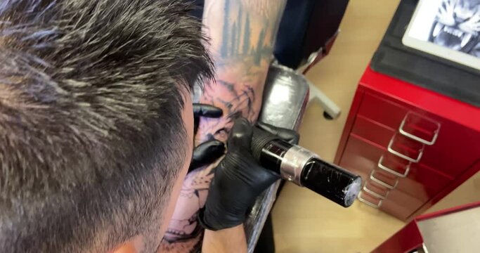Amazing overhead shot of a professional tattoo artist's tattoo process as he works his design on a man's arm.