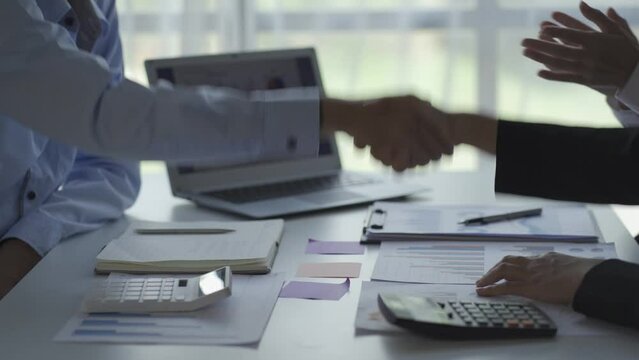 business people shaking hands in a meeting Mature businessman shaking hands to seal a deal with his partner and colleagues in office.