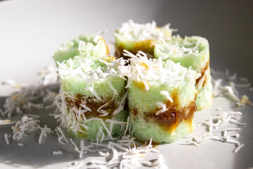 Kue Putu or Indonesian Putu bamboo Cake, traditional cake made from rice flour, palm sugar, and grated coconut. Served on white ceramic plate background.
