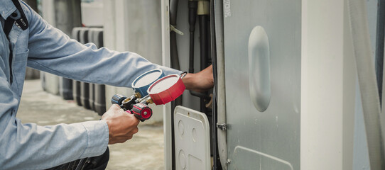 Mechanic  air conditioner technician is using a manifold gauge to check the refrigerant in the system to inspect and repair the outdoor air compressor. - obrazy, fototapety, plakaty
