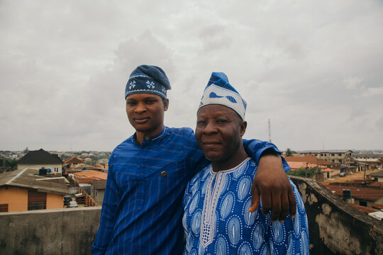 African elderly father side hugging young adult son at the rooftop